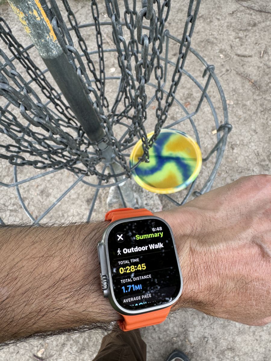 A disc dropping into the chains, with a watch on the wrist below reading 28 minutes 45 seconds and 1.71 miles